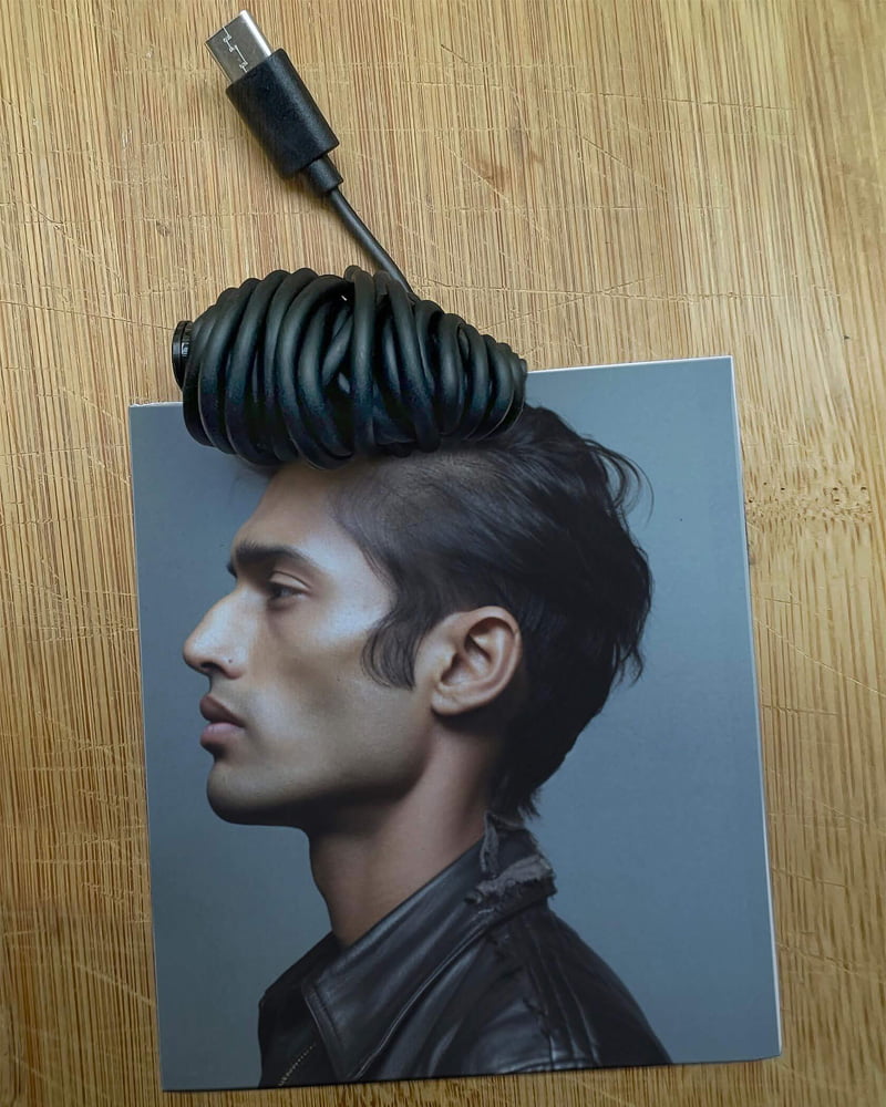 Combined photo of black charging cable and black hair of a young man