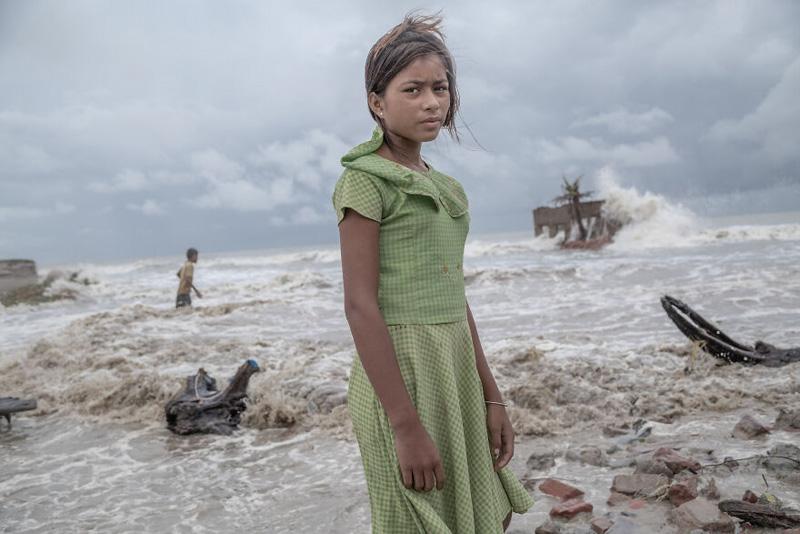 A girl among the ruins buried in the water in the Sundarbans maritime forest, Bay of Bengal