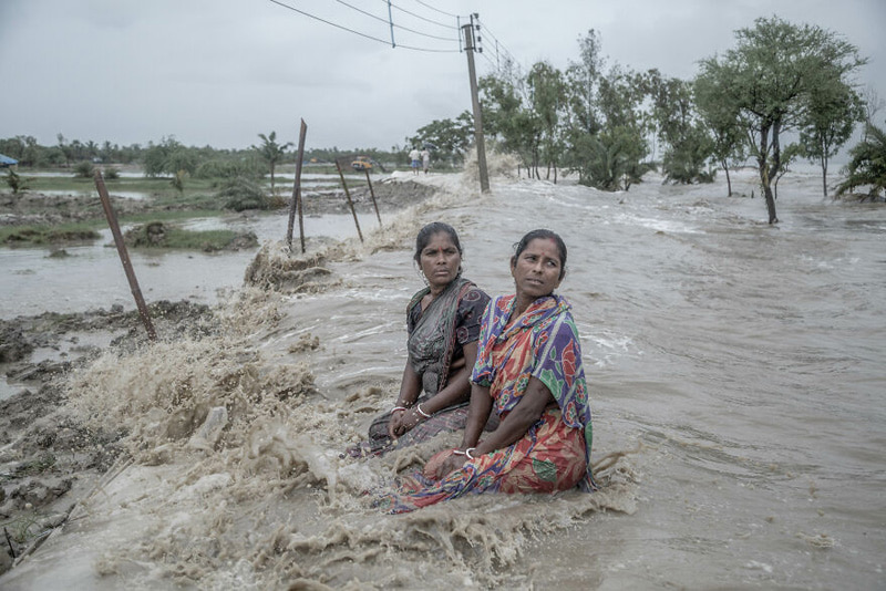 Two Indian women in the middle of the water waves that washed away their houses