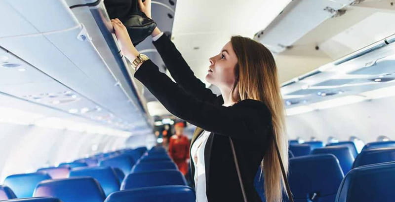 Placing a handbag in an airplane compartment, photo source: onmanorama, photographer: unknown