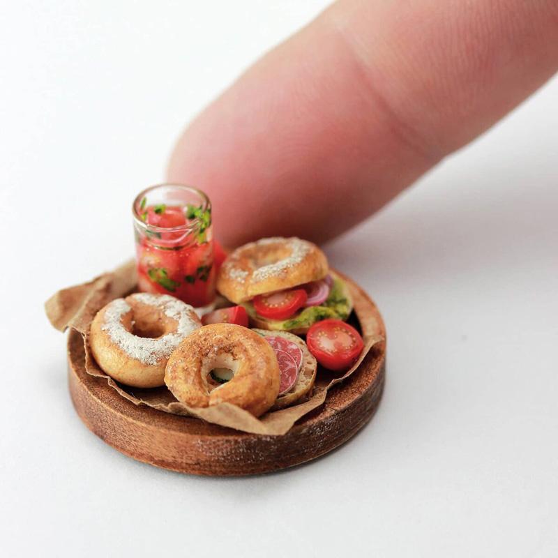 A miniature dish containing bagel bread and vegetables made by Shai Aaron