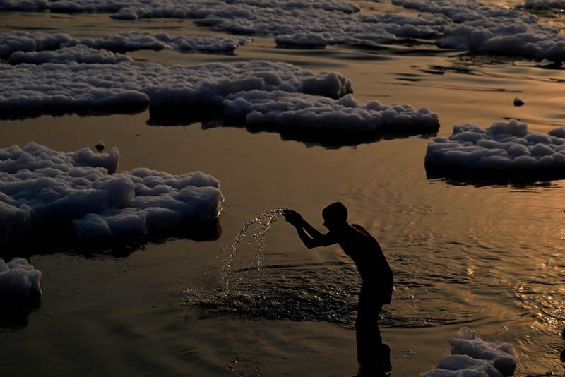 A man prays in the polluted, sediment-filled waters of the Yamuna River in New Delhi at sunrise; Photo source: the guardian; Photographer name: Sajjad Hussain