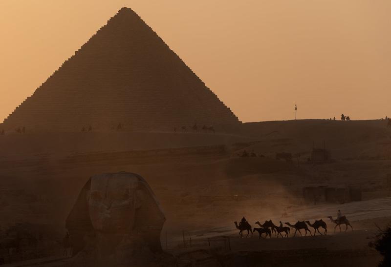 Tourists ride camels in Egypt between the Sphinx and Menkur, the smallest of the three pyramids. Source: theguardian; Photographer: Unknown 