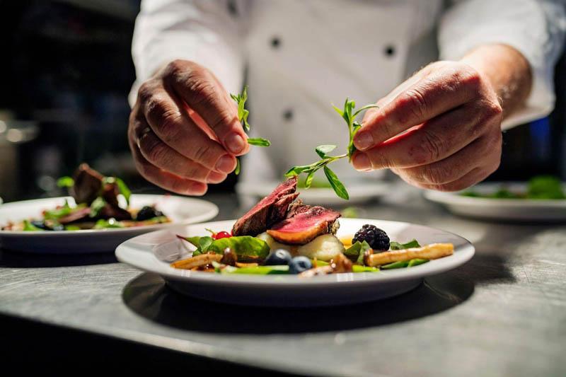 A chef decorating a plate of food; Photo credit: OysterLink; Name of the photographer: unknown