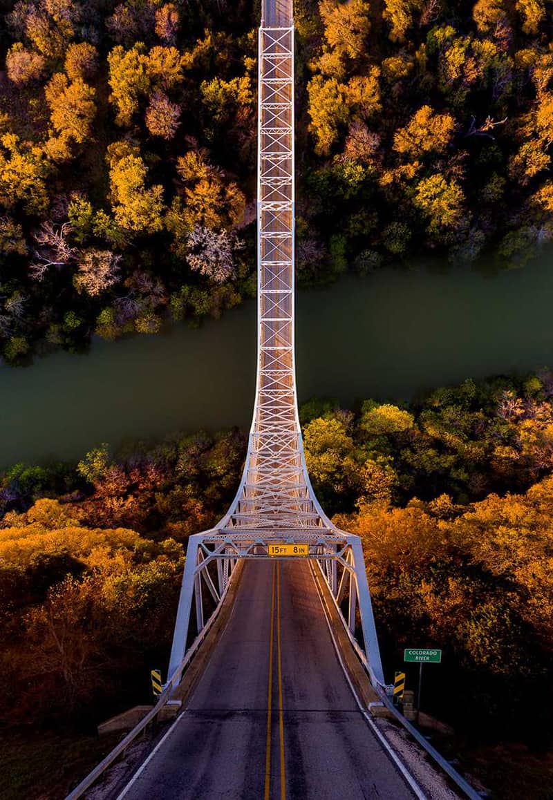A panoramic photo of a bridge between the forest and the river