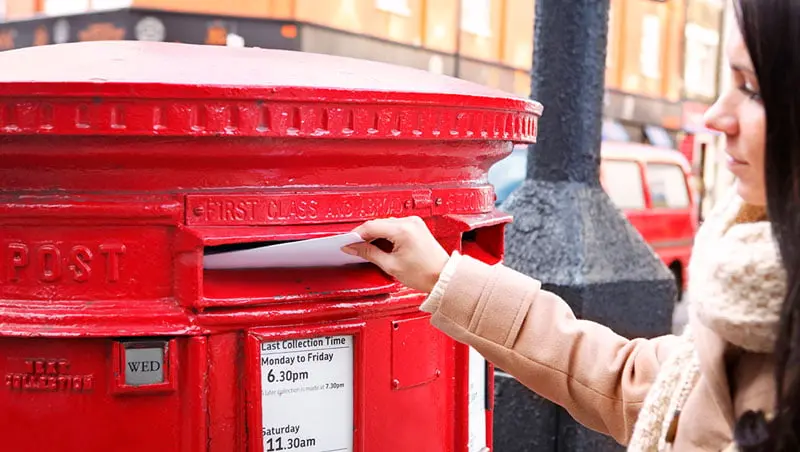 A woman next to the mailbox; Photo Source: ofcom.org.uk; Photographer's name: Unknown
