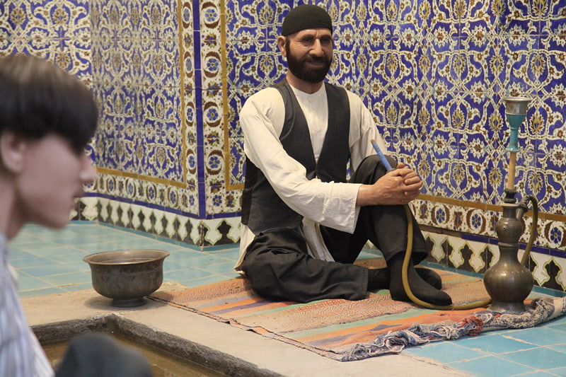 A statue of a man with a black vest and hookah in Ganjali Khan Kerman bath; Photographer: Mohammad Shojaee
