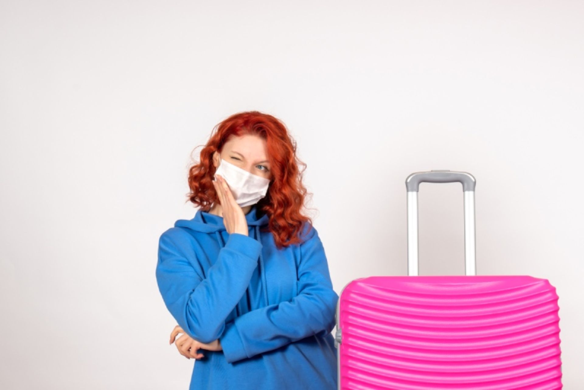 A girl with blue blouse next to the pink suitcase