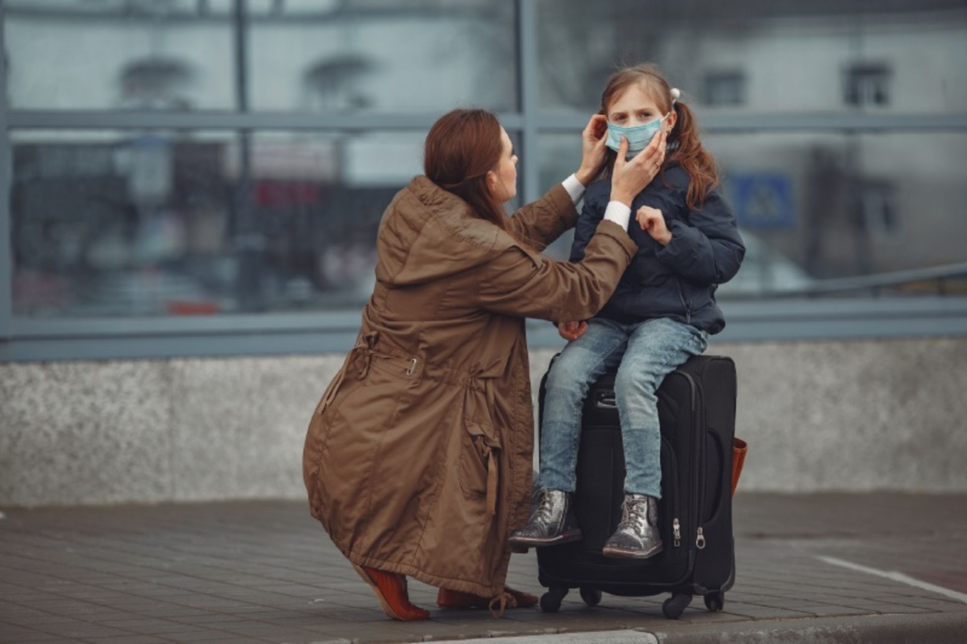 Mother with a brown dress and a little girl with a suitcase