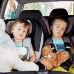 Two children sleeping in a special seat in the car