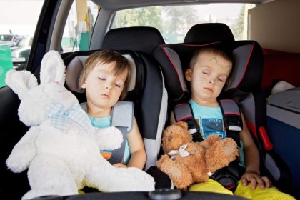 Two children sleeping in a special seat in the car