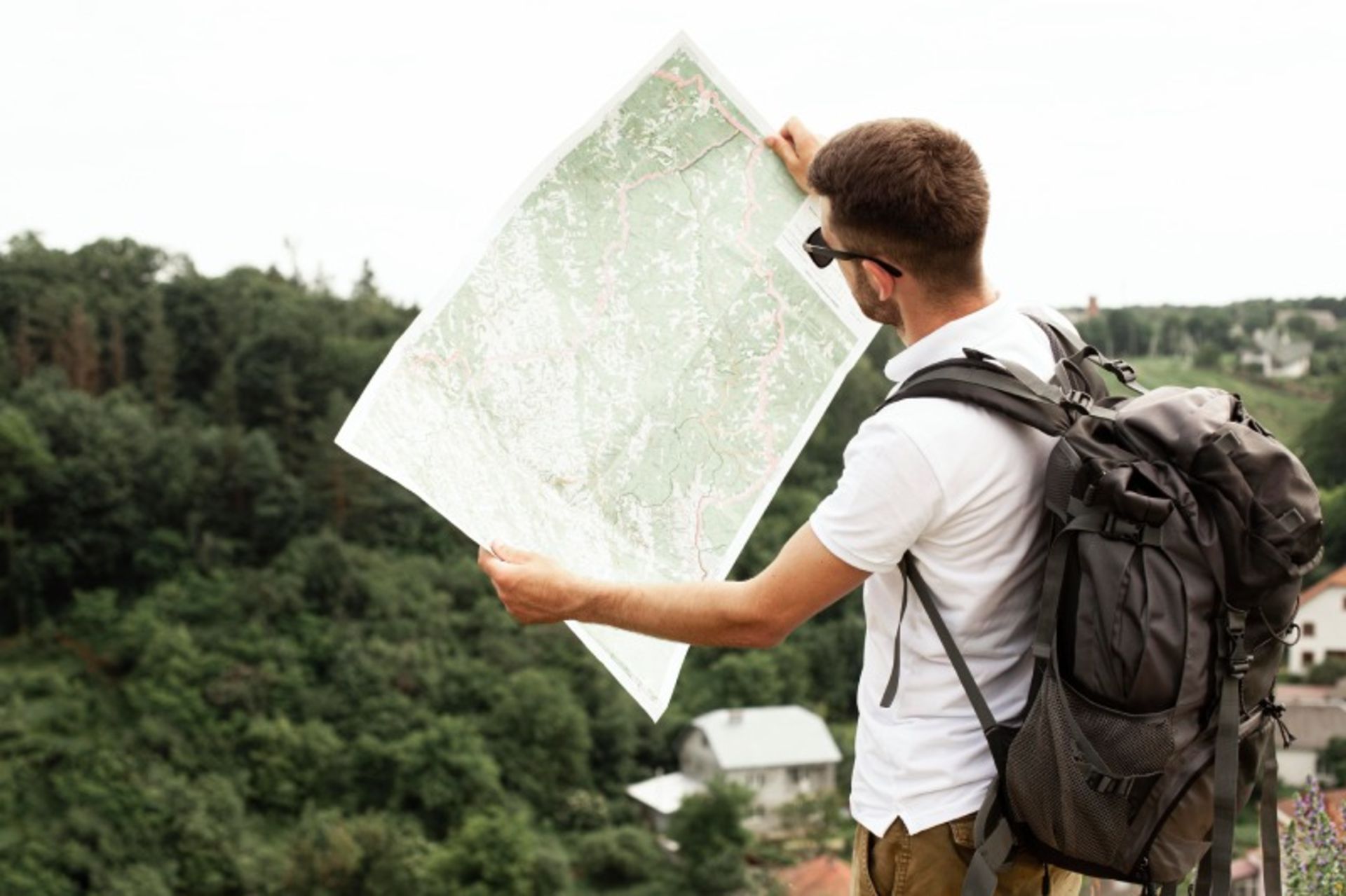 A man with a bag and paper map in nature
