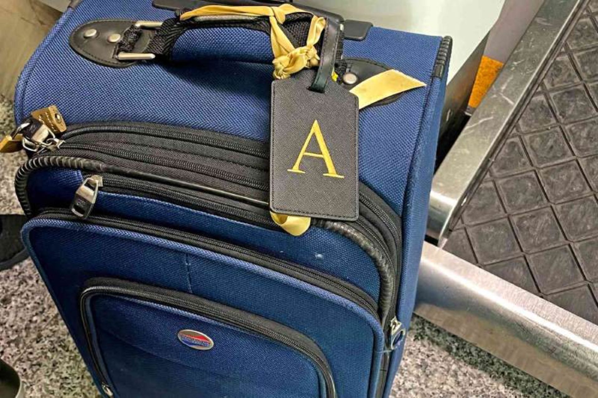 English letter tag with yellow ribbon attached to blue suitcase