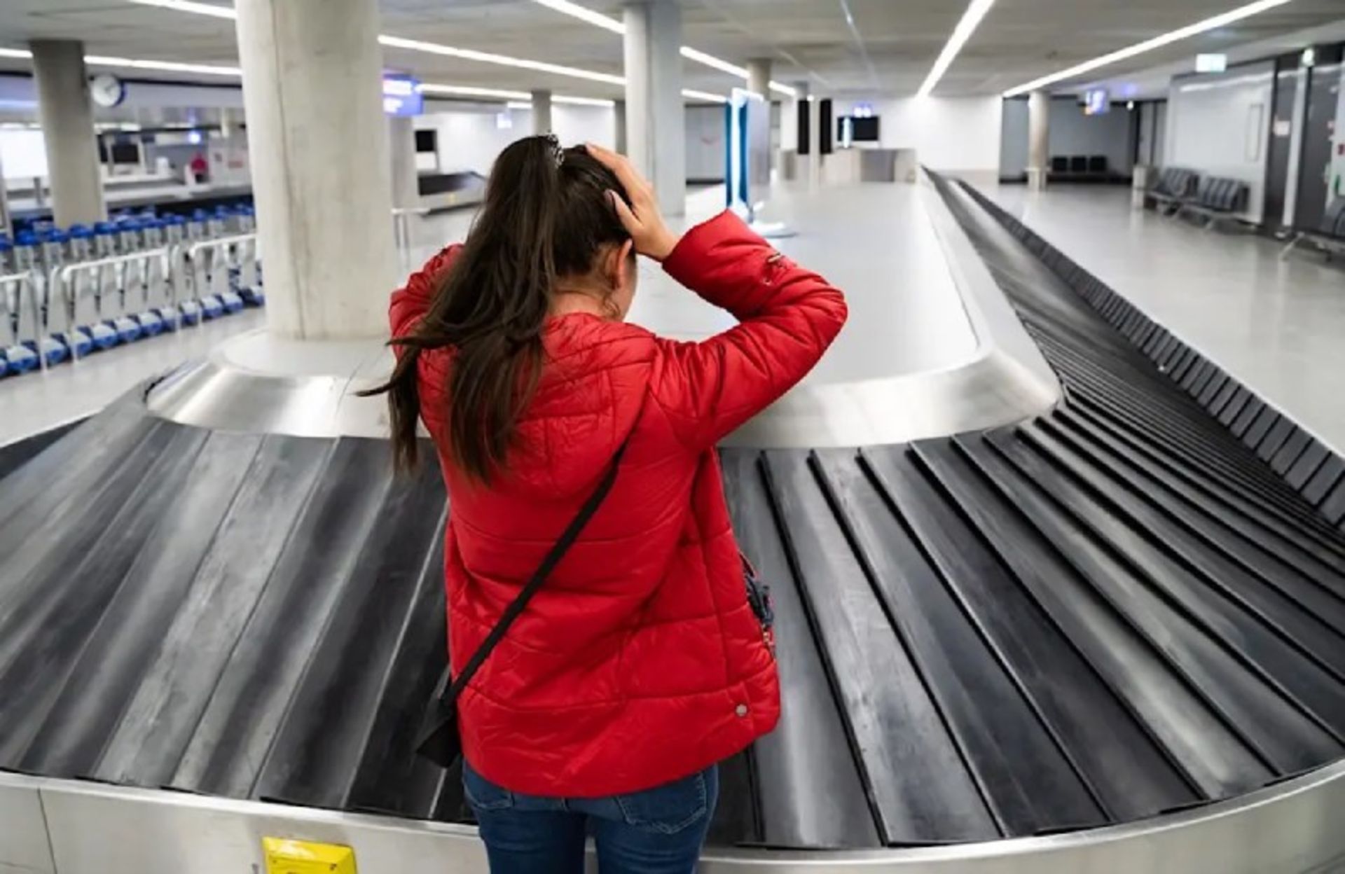 A woman in a red dress facing the airport conveyor