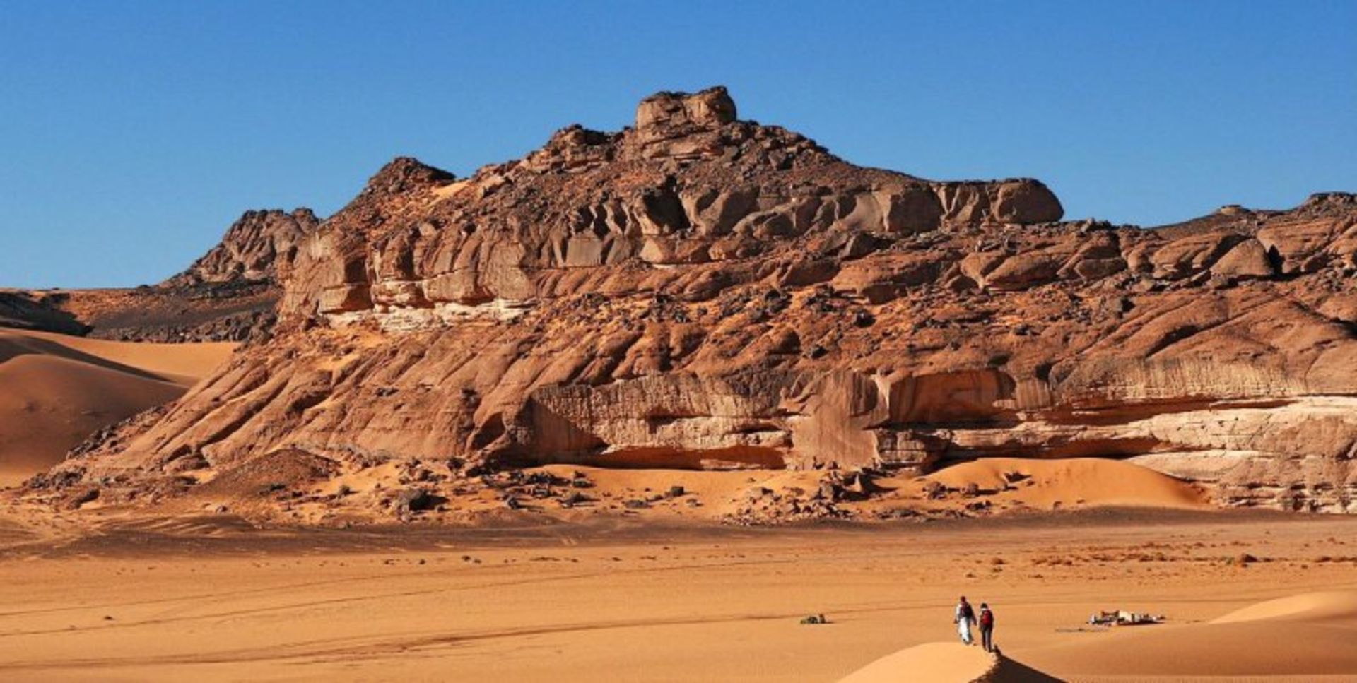 Sands, mountains, flat and blue sky and two people in the desert desert