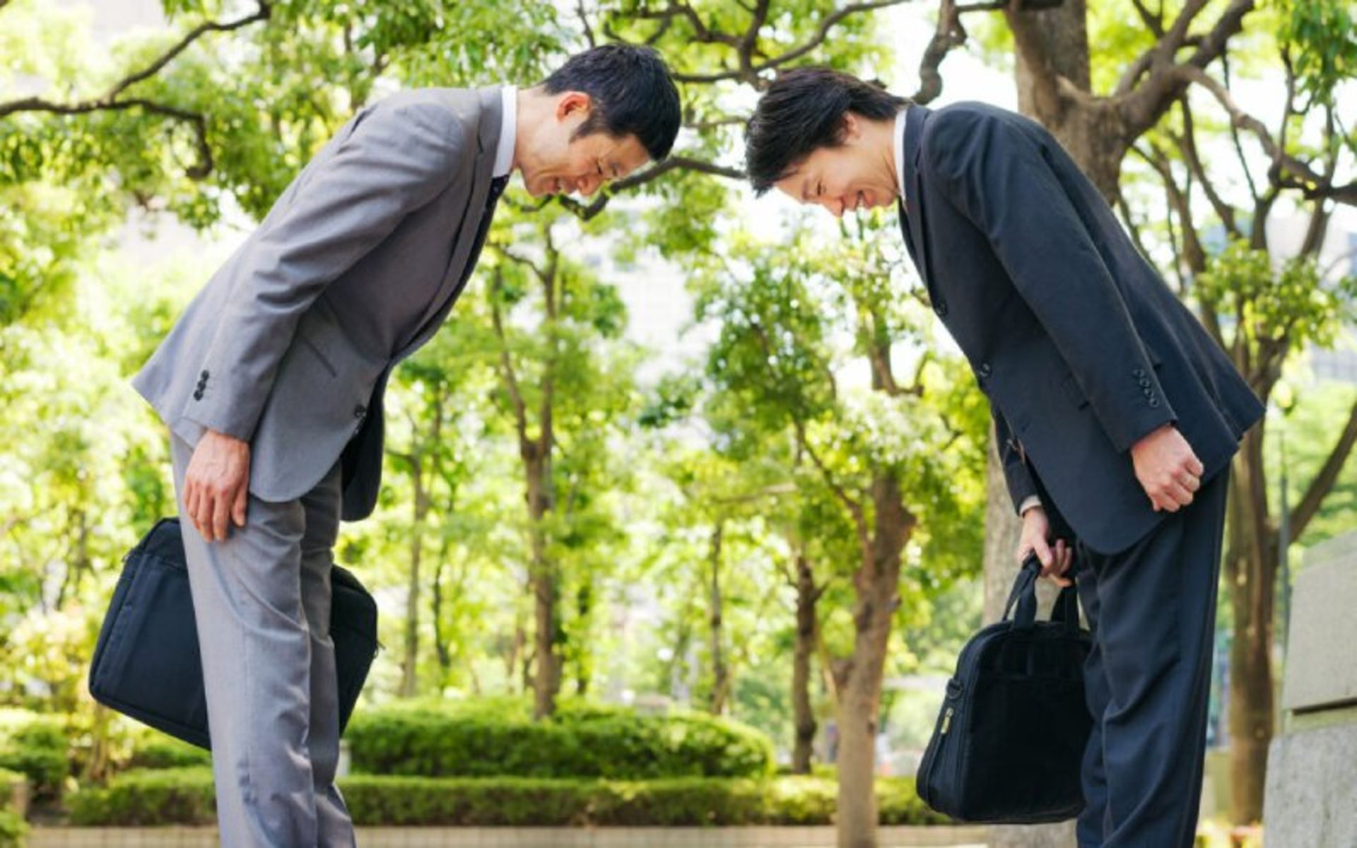 Two Japanese men with a suit bowing to each other 