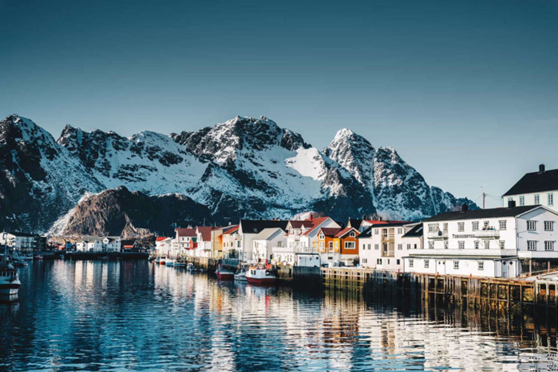 A beach village in Norway with colorful houses and snowy mountains