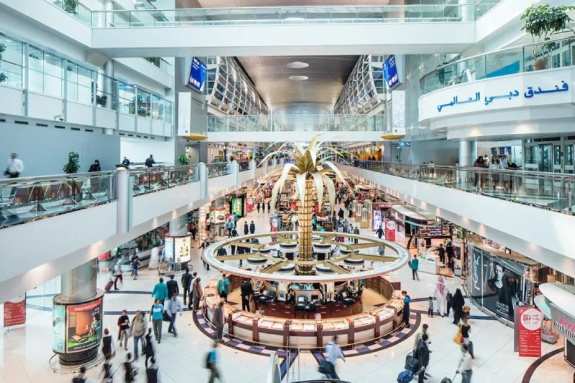 Golden Palm statue and passengers indoors Dubai International Airport 