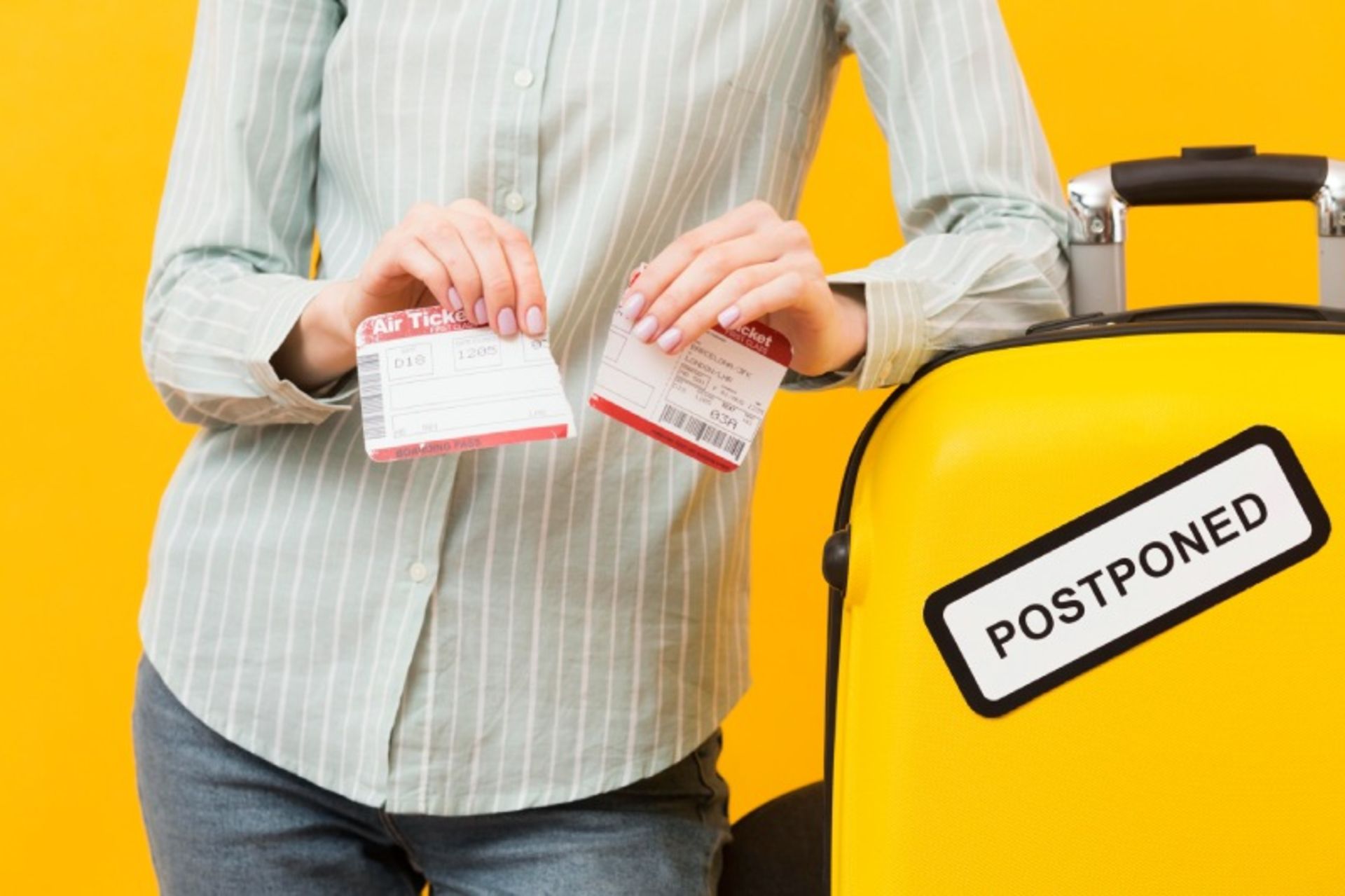 A woman tearing the travel ticket next to the yellow suitcase