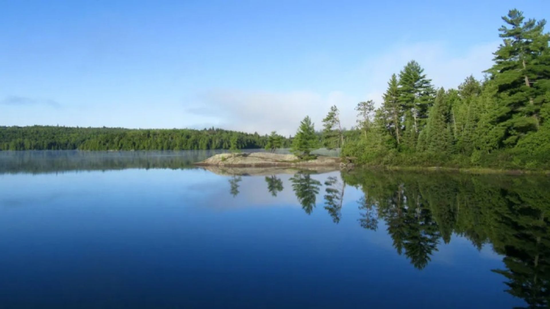 Reflection of trees and blue sky on Lake Rock in Ontario