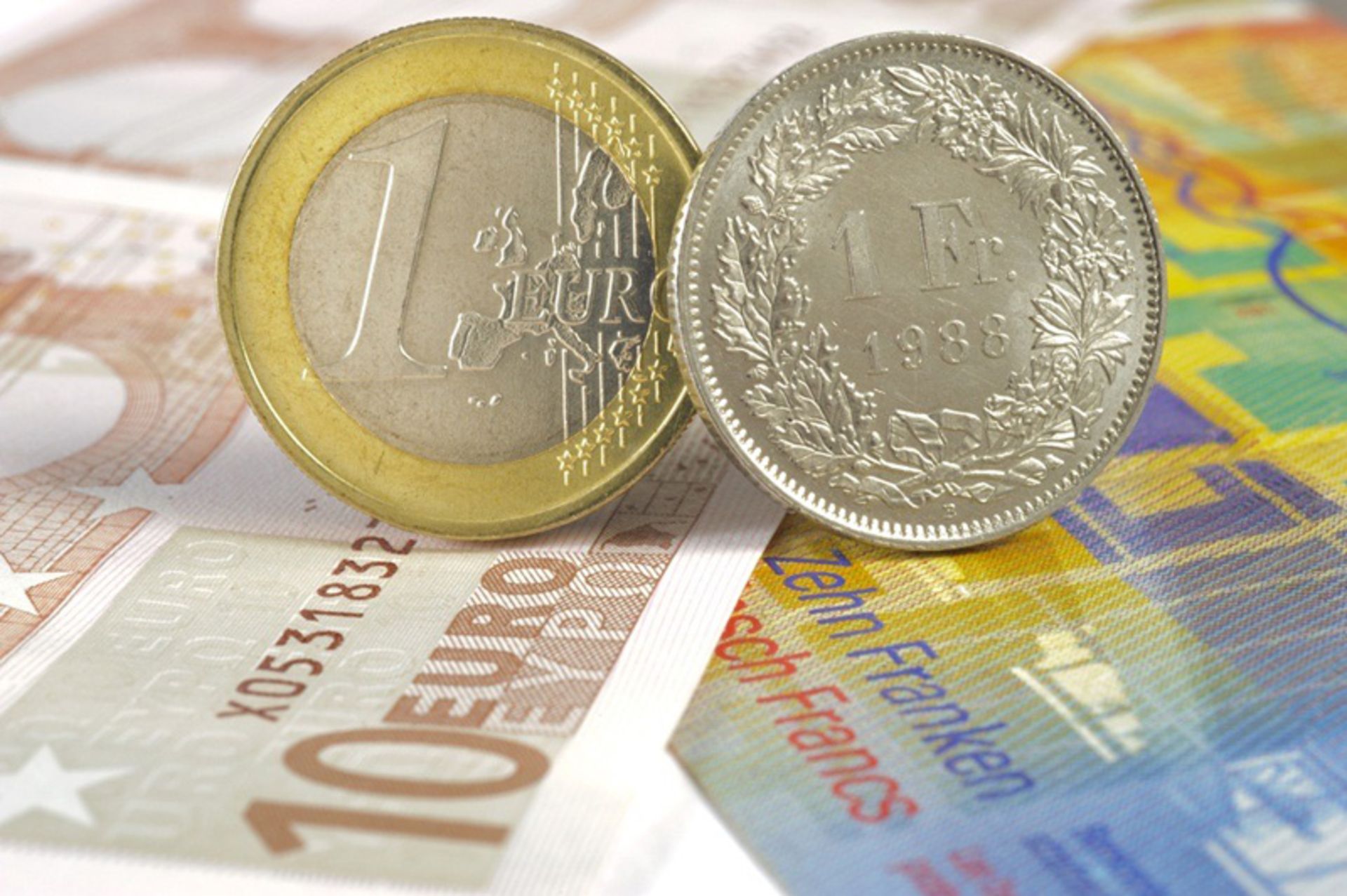 Euro coin and Swiss franc on Euro and Frank banknotes