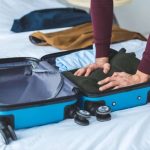 A man putting clothes inside the suitcase