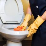 Service working while cleaning toilets with gloves