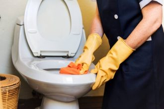 Service working while cleaning toilets with gloves