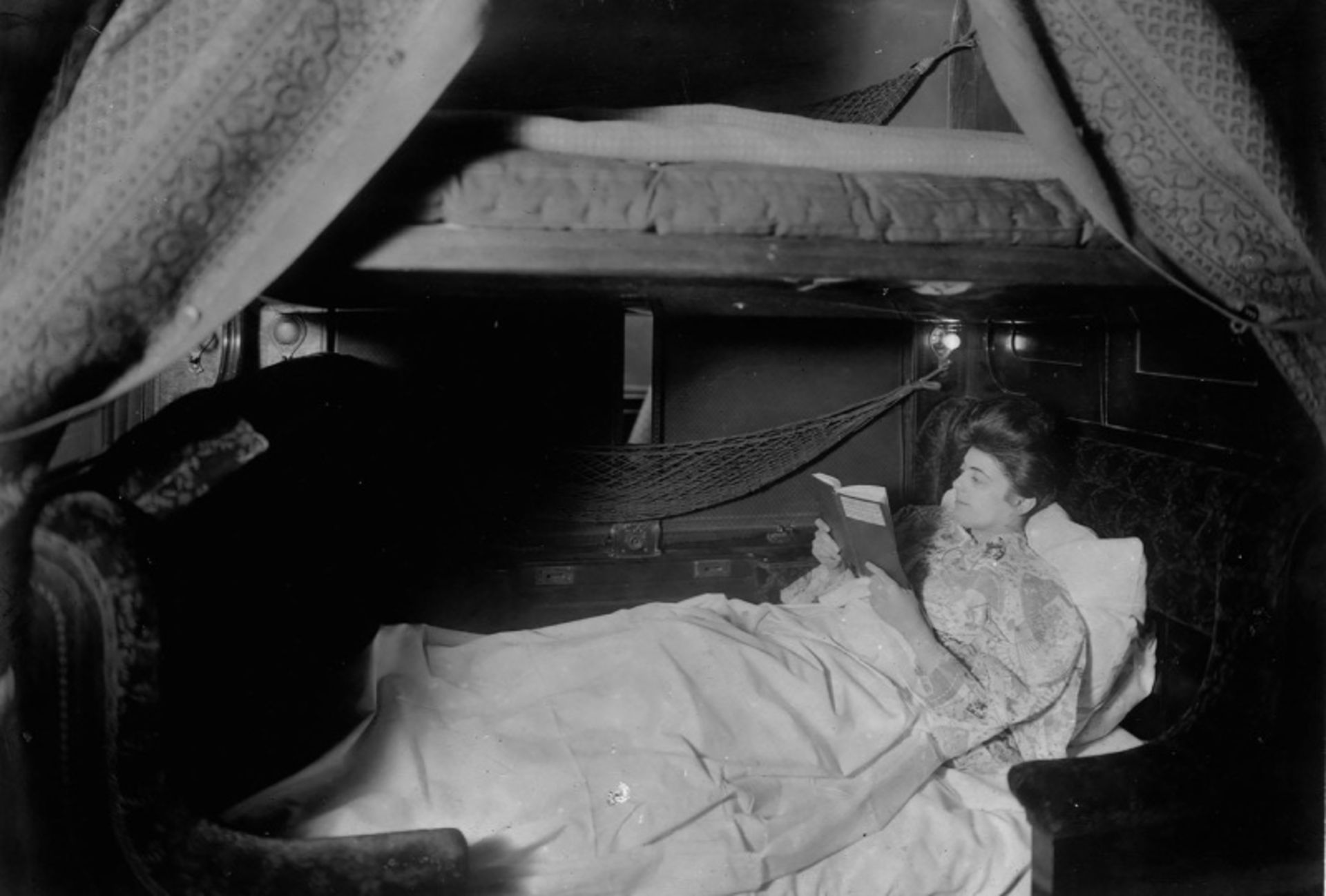 A woman on the bed studying in the old train wagon