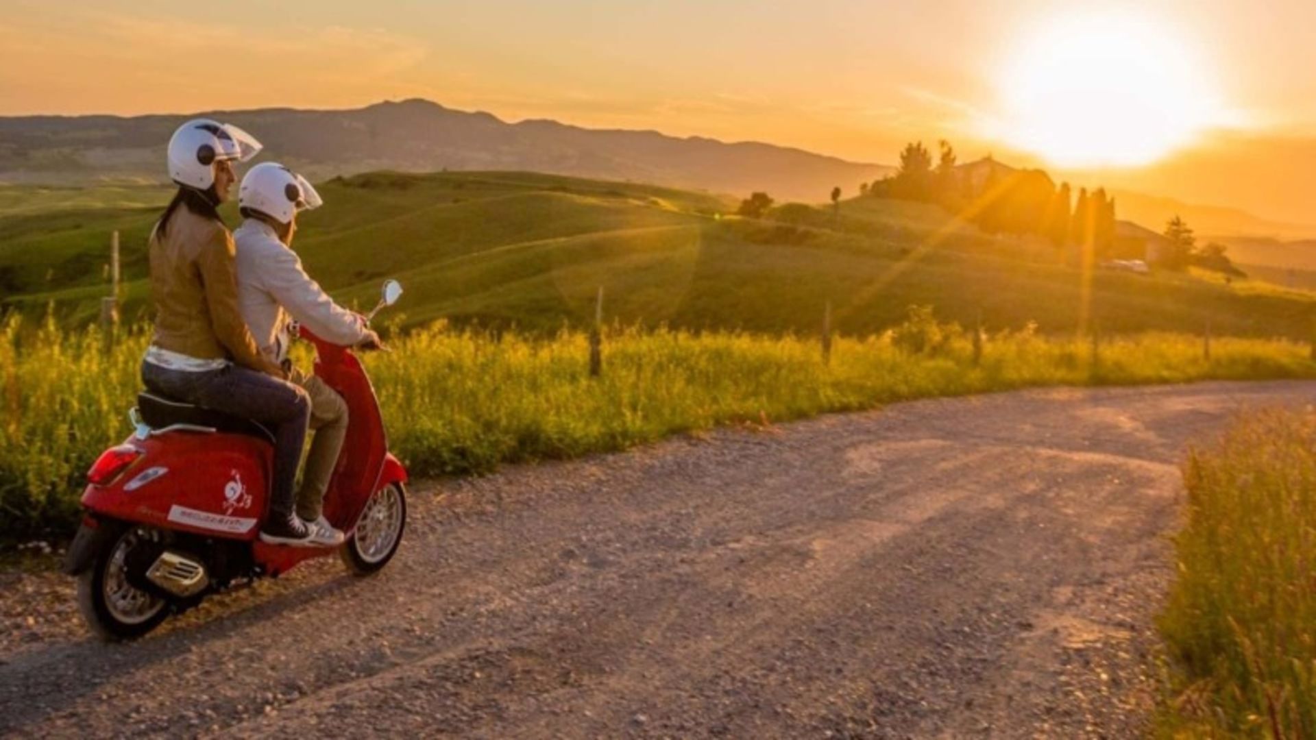 Riding with Scooter Vespa at sunset in Tuscany nature
