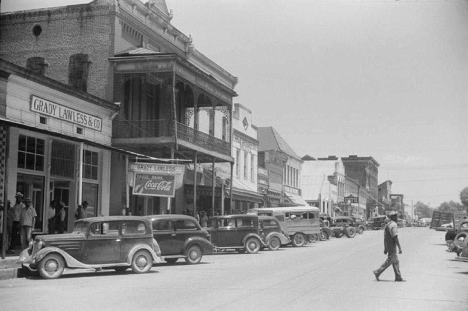 Old image of vehicles on the main street of Greensburo