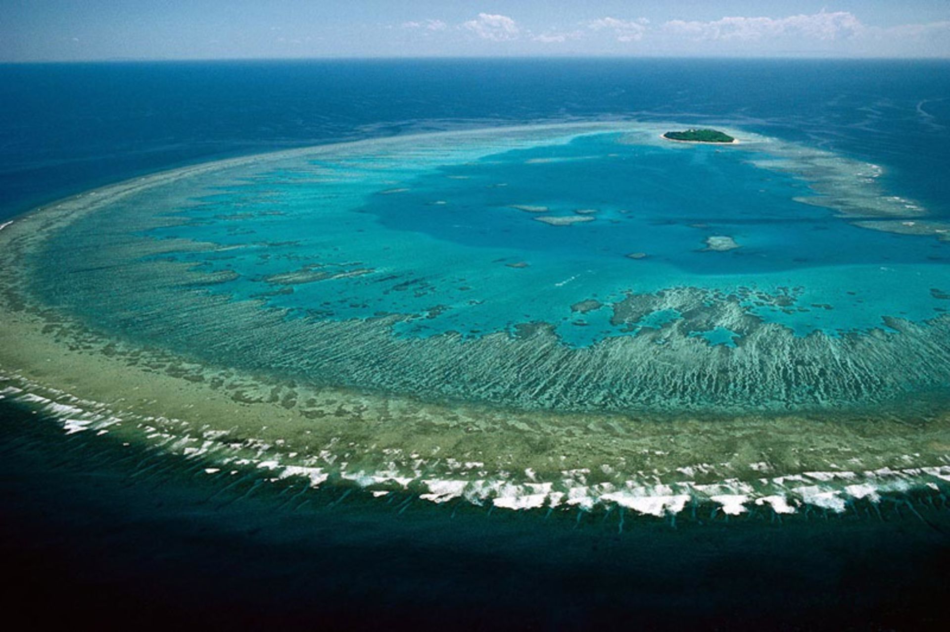 Great coral reef with turquoise waters and a small island in distant