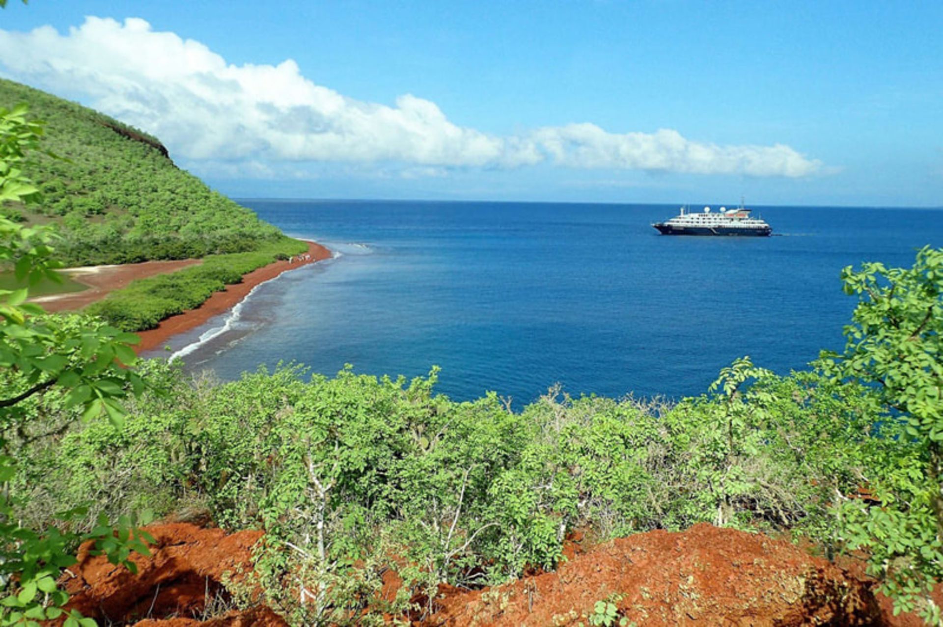 A view of Galapagos Beach with green hills and brown beach