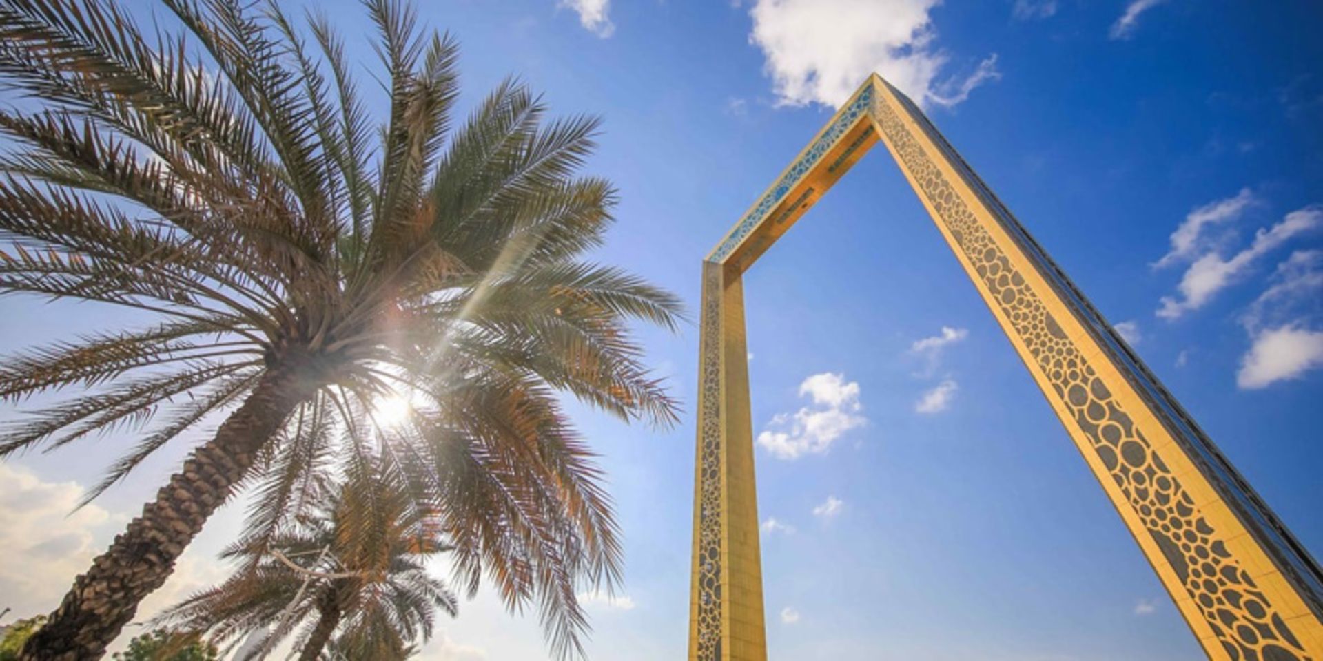 The golden structure of the Dubai frame next to the palm tree