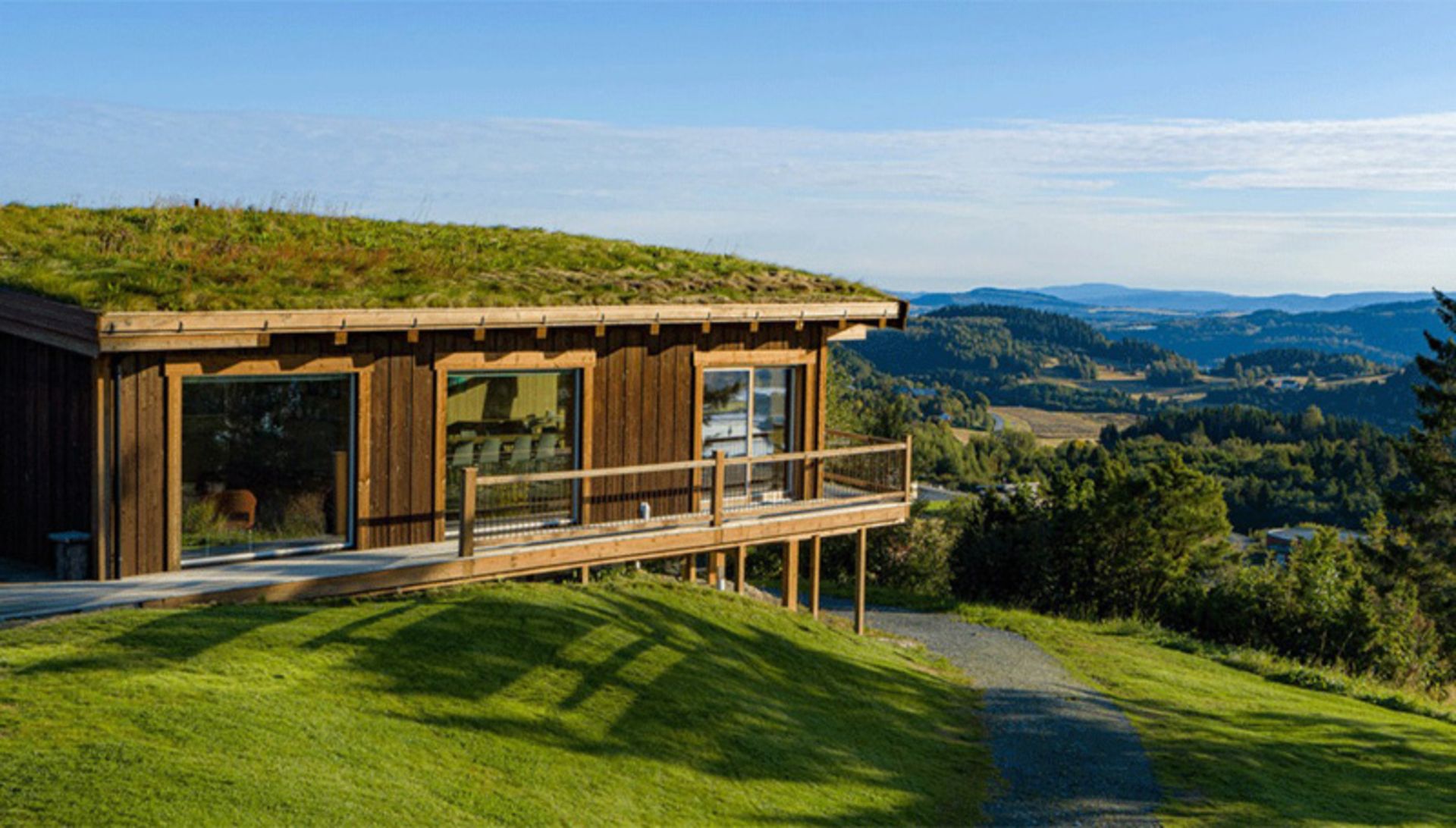 The wooden structure of Hotel Evina, Norway, on a green hill