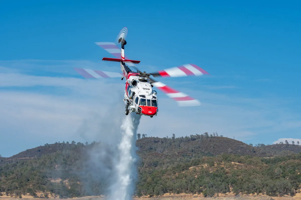 Pouring water on fire by S-70i helicopter