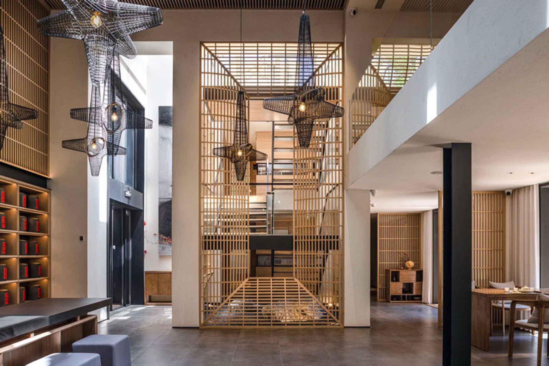 Two-story interior view of Blue Lake Teahouse with lattice chandeliers and wooden shelving