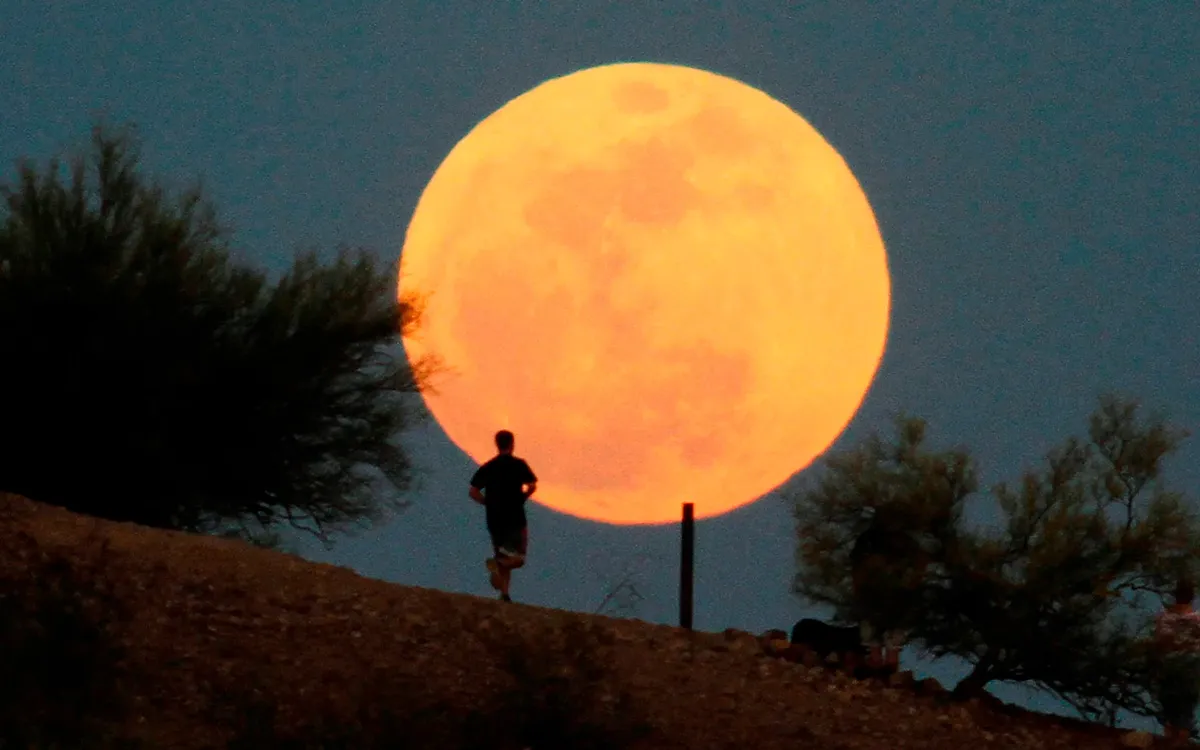 A runner traverses a hill course in front of a supermoon over Papago Park in Phoenix in May 2012.
