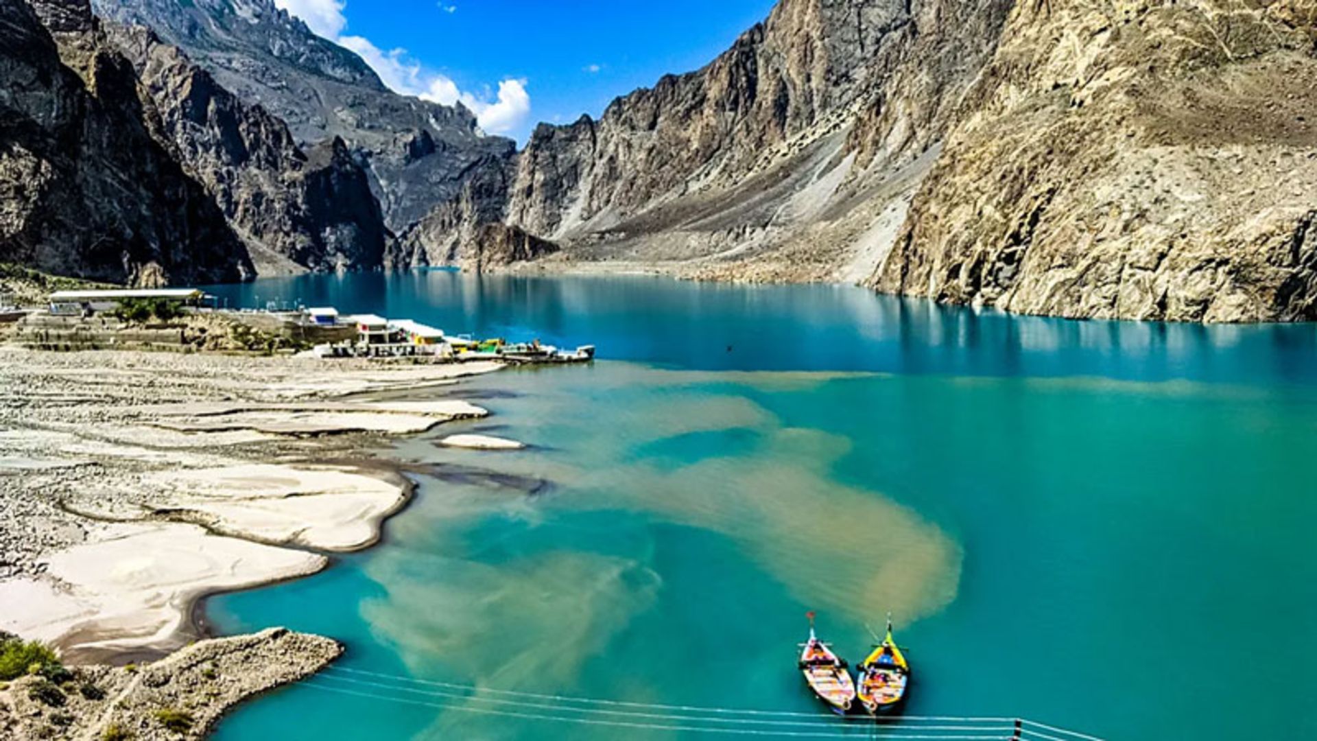 Colorful boats in the turquoise waters of Attabad Lake and the surrounding mountains