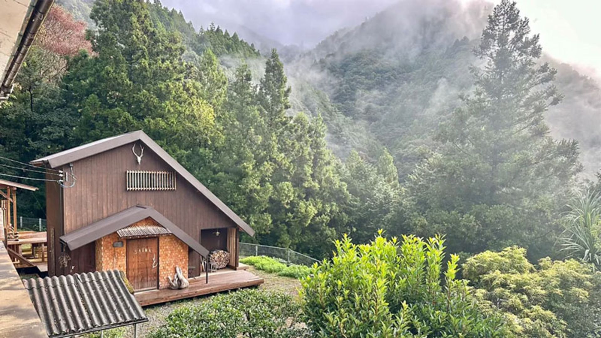 A log cabin with a terrace and a view of the dense Japanese mountain forests