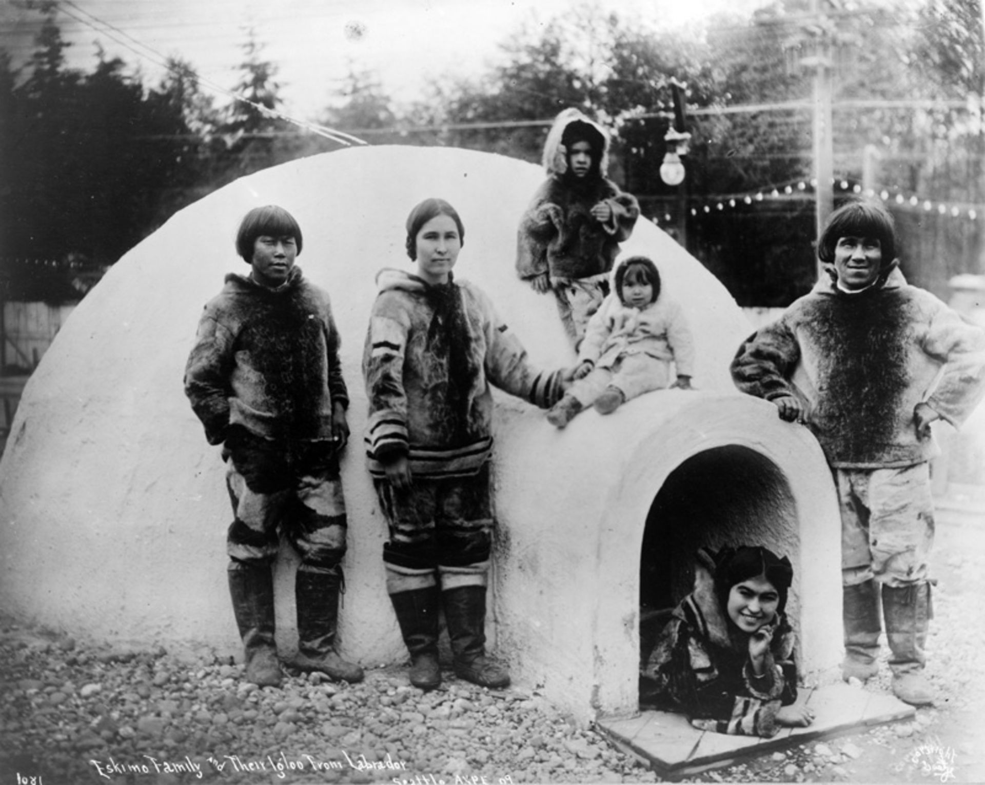 Old photo of some Eskimos next to the ice house