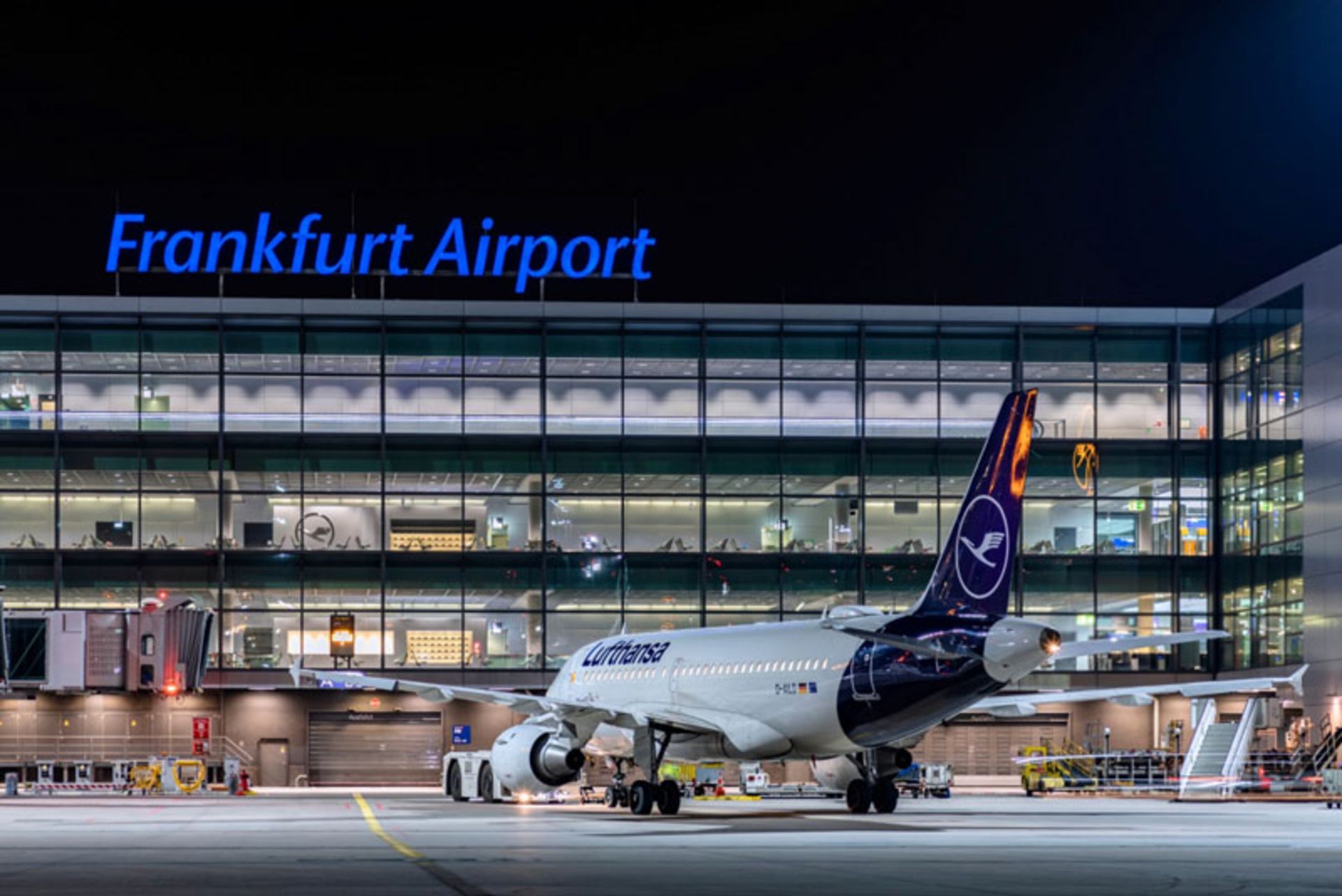 Night view of Frankfurt airport terminal with a Lufthansa plane on the runway