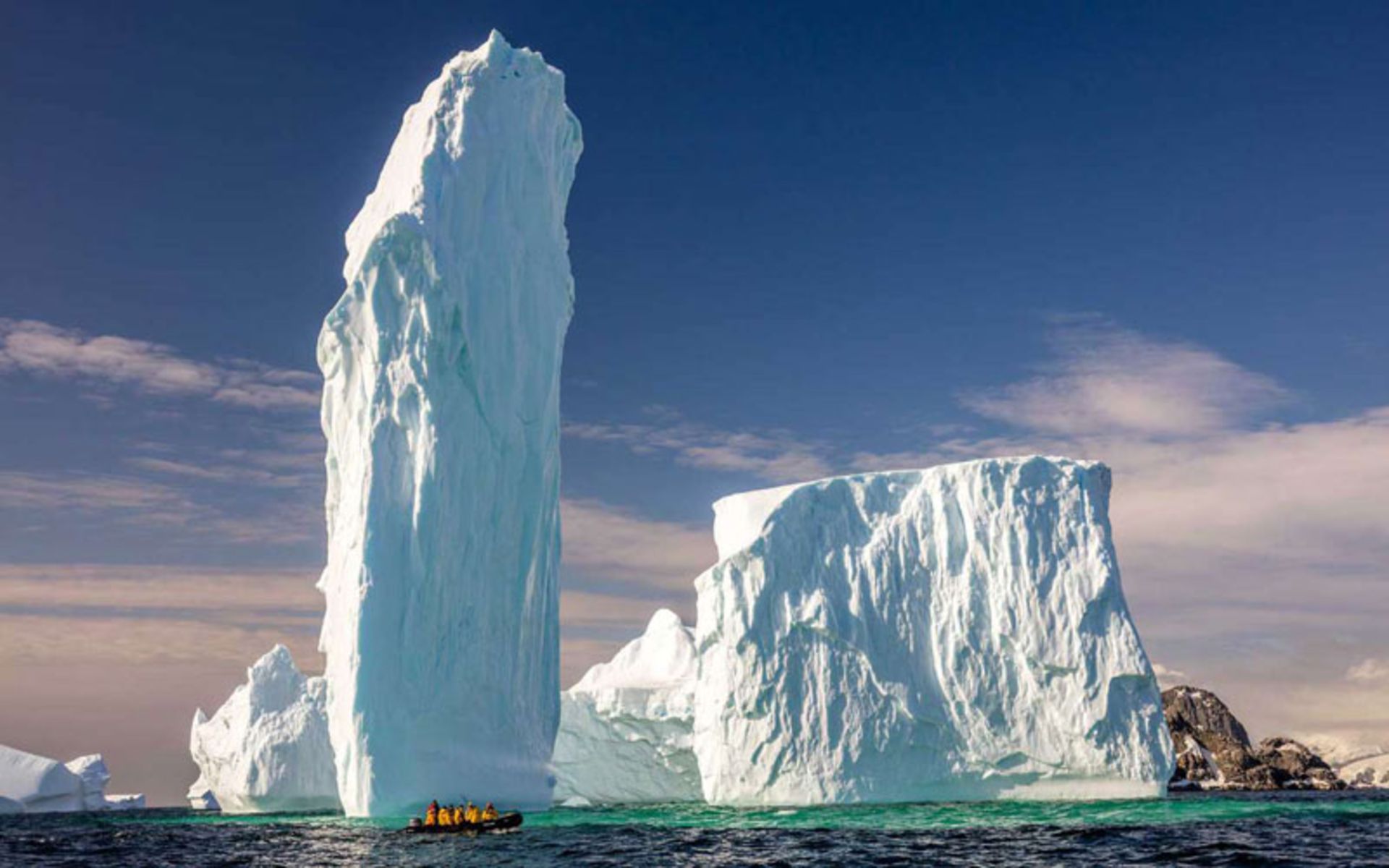 A small boat next to the giant ice columns of Antarctica