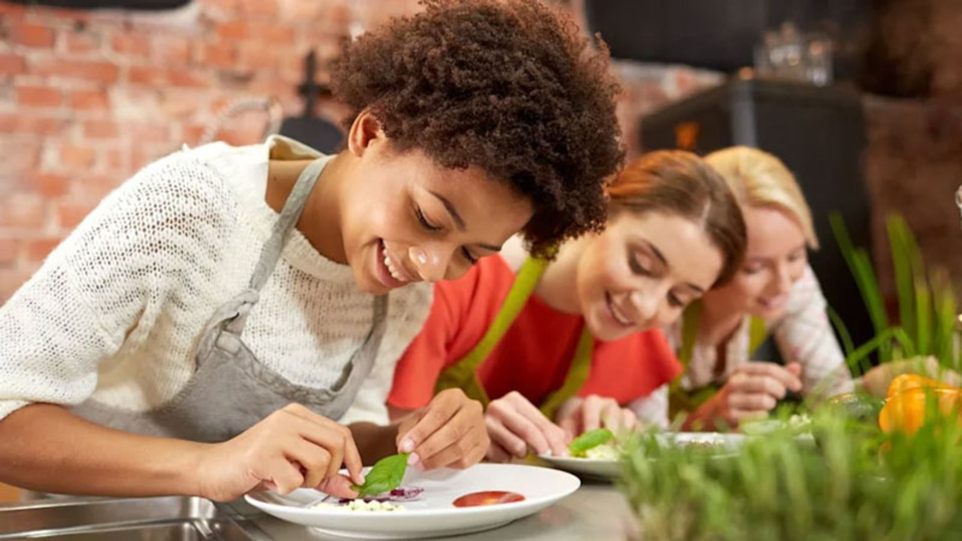 Three young women participating in a cooking and food decorating class
