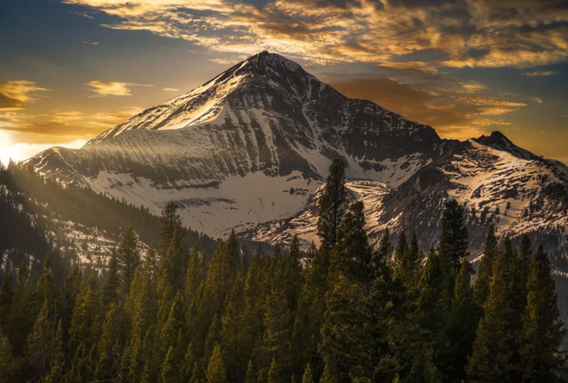 A golden sunset over a snow-capped peak in Montana's Big Sky