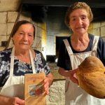 Two grandmothers in front of an ancient wood oven