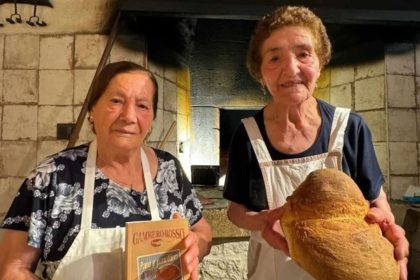Two grandmothers in front of an ancient wood oven