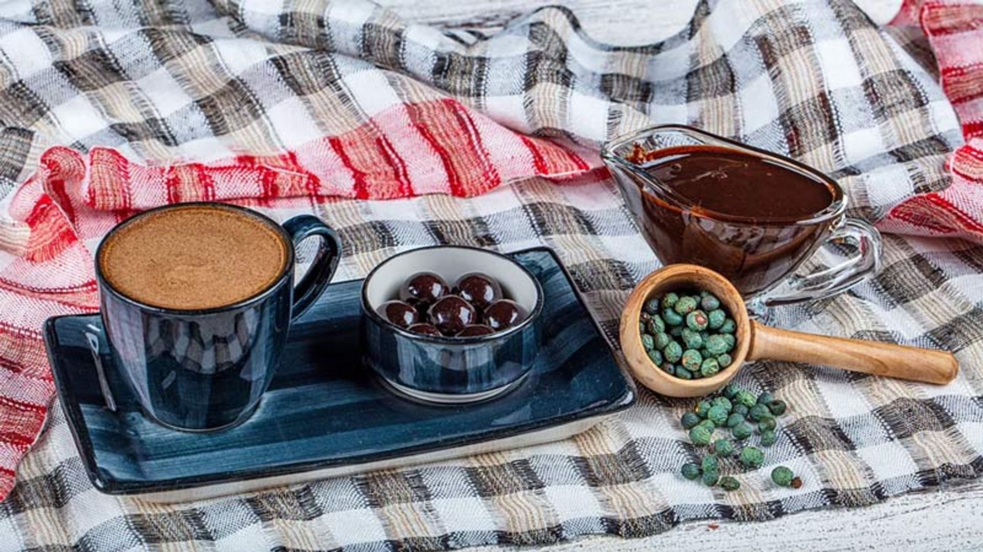 A cup of coffee, a bowl of meningich dark dough, a wooden spoon with nuts and chocolate