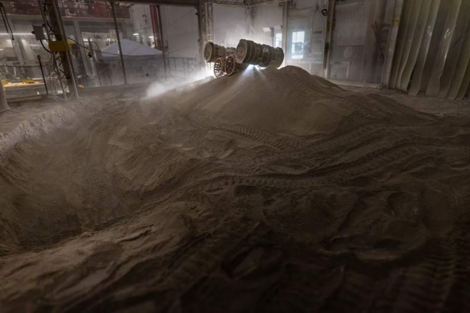 A rover experimenting with digging into a mound of simulated lunar soil 