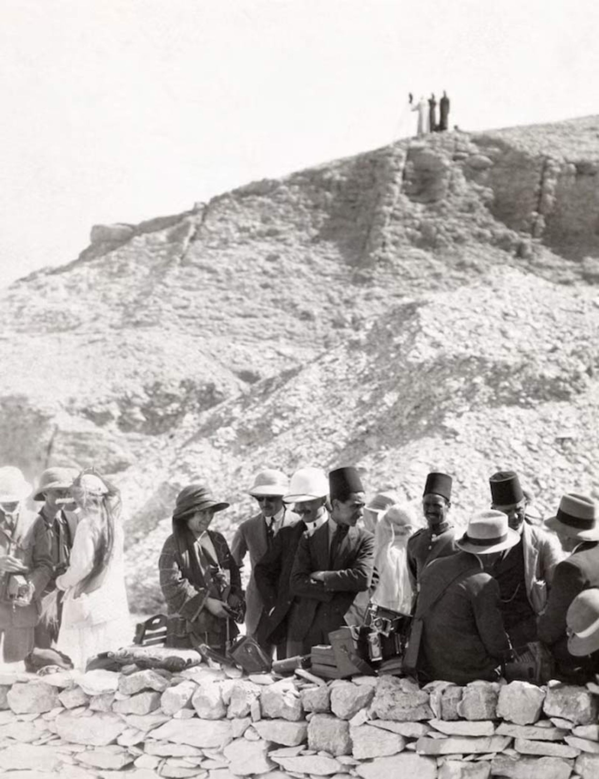 A group of men in 1920s formal clothes and brimmed hats talking